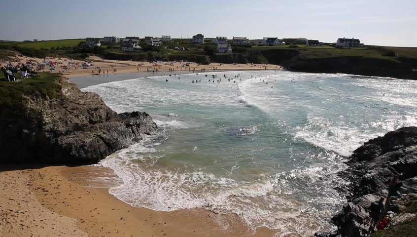 Many people swimming in waves Treyarnon Bay Cornwall England UK Cornish north coast between Newquay and Padstow on a sunny summer blue sky day