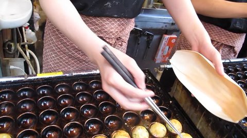 Cooking takoyaki is a ball-shaped Japanese snack at Dotonbori in Osaka, Japan Stock Video