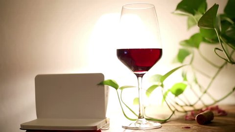 woman writing in her notepad over a glass of red wine in a romantic and intimate background
