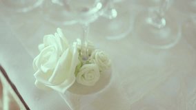 Footage of champagne flutes decorated with flower on table. Panning shot of alcohol glasses during wedding celebration.
