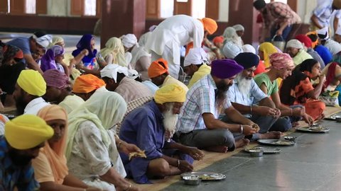 AMRITSAR, INDIA - SEPTEMBER 26, 2014: Unidentified poor indian people eating free food at a soup kitchen in the Golden Temple