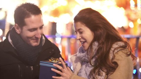 Young man surprise his girlfriend with a Christmas gift outdoors at Christmas fair. Shot on RED Epic.