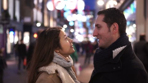 Portrait of happy romantic couple kissing on busy city street at Christmas time. Shot on RED Epic.