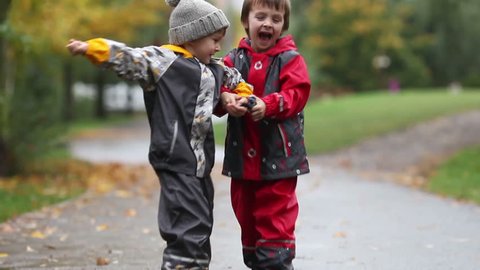 Two children, fighting over toy in the park on a rainy day, autumn time