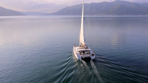 Young people ride on a catamaran boat at sea bay - Aerial view