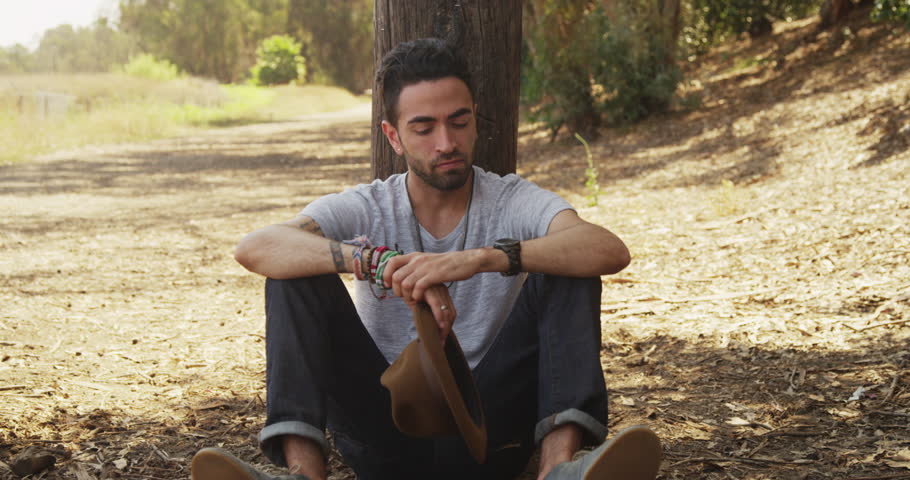 Attractive Hispanic man sitting outdoors smiling at camera