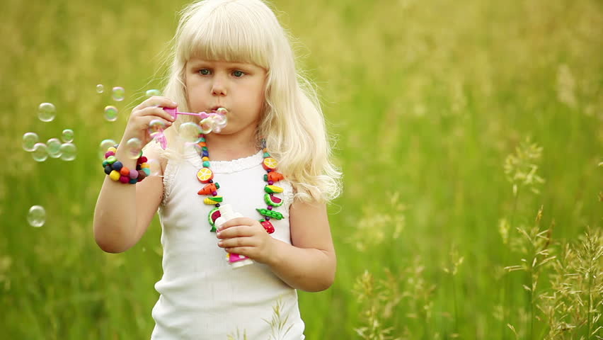Baby blonde blowing bubbles. She laughs and looks at camera. 