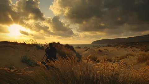 Cinemagraph Loop - Photographer on a sandy beach overlooking the ocean. Motion photo วิดีโอสต็อก