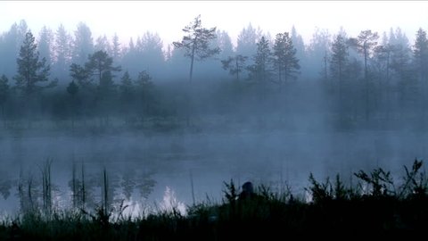 Early morning fog and mist above a quiet lake in Finland timelapse