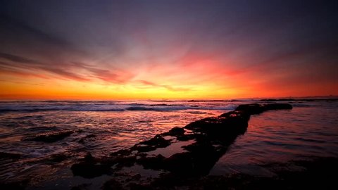 Cinemagraph Loop - Orange sunset over ocean waves crashing a breakfront. Motion photo