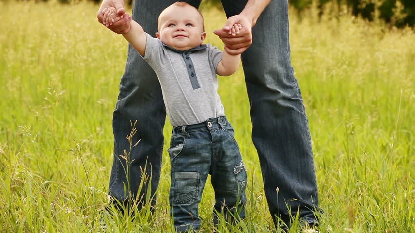 Baby boy learns to walk with father. 