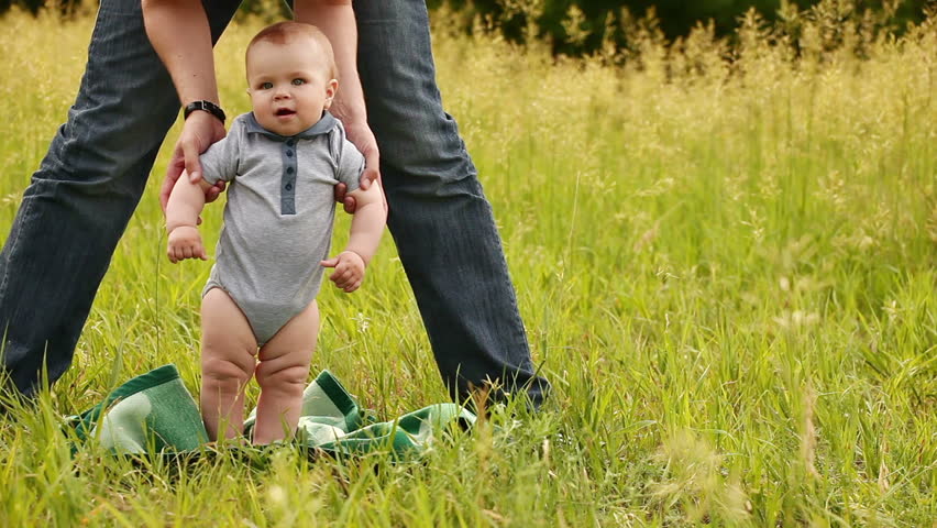 Baby learns to walk outdoors. 