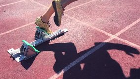 Athlete in gold shoes sprinting in slow motion from the starting blocks over the starting line of a race on a red running track  - Powered by Shutterstock - Get 15% off with code: PIKWIZARD15