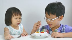 Asian siblings eating cake together in living room 