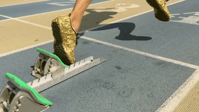 Athlete in gold shoes starting a race in slow motion from the starting blocks on a blue running track  - Powered by Shutterstock - Get 15% off with code: PIKWIZARD15
