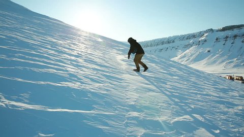 A man trying to climb the mountain on a slippery frozen snow, slips and falls.