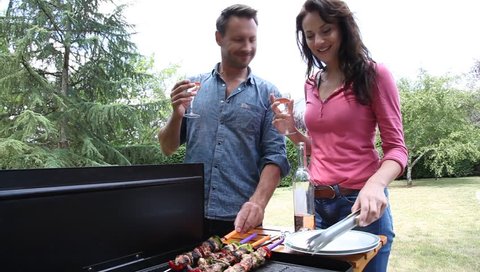Happy couple cooking meat on barbecue grill