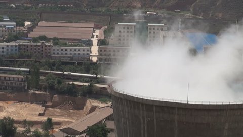 Closeup of a coal fired powerplant in the Chinese city of Lanzhou. A train is passing by in the background.