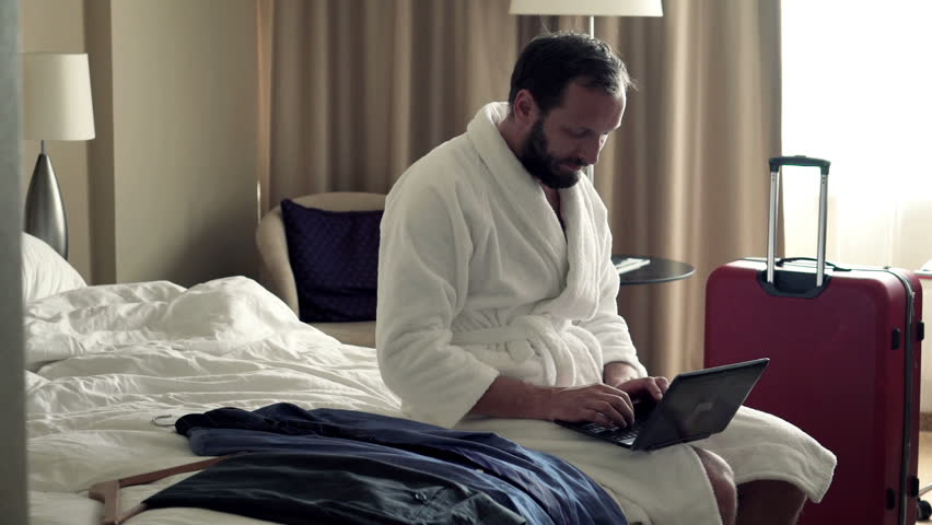 Young businessman working on laptop sitting on bed in hotel room 
 | Shutterstock HD Video #12157703