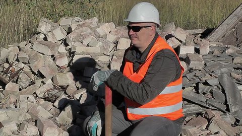 Tired construction worker near a pile of bricks