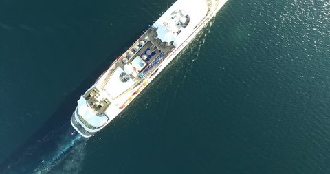 Aerial view of luxury medium cruise ship sailing from port on sunrise through the bay
