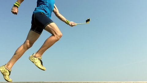 Modern athlete running in slow motion with his smartphone on the end of a selfie stick