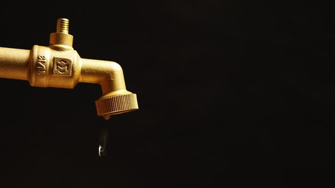 Faucet is dripping and flowing slowly on a black background

