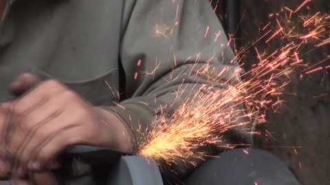 Sparks light up as a worker in China's Xinjiang province is sharpening a knife.