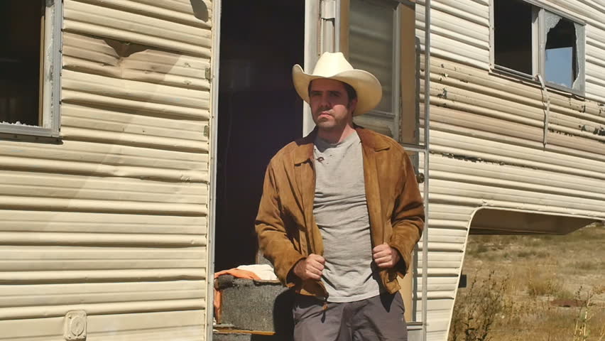 Western man next to abandoned  trailer