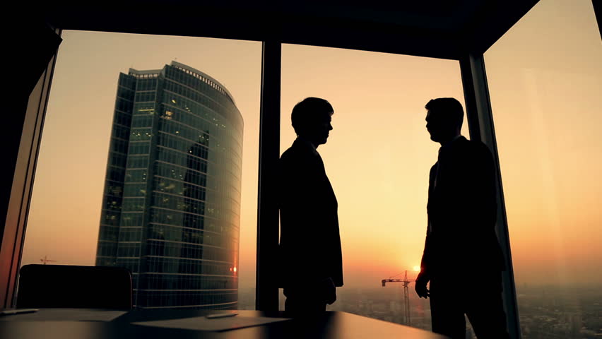 silhouette of two businessmen talking and shaking hands standing by the window at sunset, the construction of a skyscraper and crane in the background Royalty-Free Stock Footage #12178793