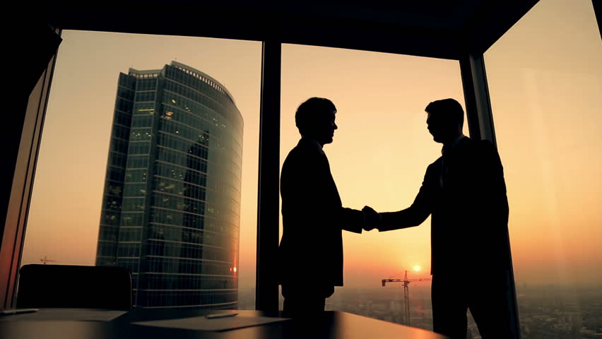 Silhouette of two businessmen talking and shaking hands standing by the window at sunset, the construction of a skyscraper and crane in the background | Shutterstock HD Video #12178793