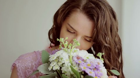Beautiful girl in a pink dress inhales aroma of a bouquet of flowers. Close-up HD