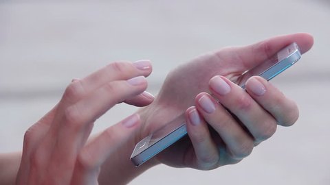 Closeup shot of female hands holding smartphone, typing text on touch screen. Woman answering friend message in social network application, searching for information. Worker spending break time online