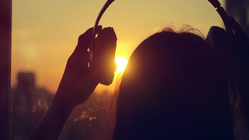 Attractive young woman wears listening to music on the music player at city blurred background with sunset. enjoying the tunes in her headphones in slowmotion. 1920x1080 | Shutterstock HD Video #12203189
