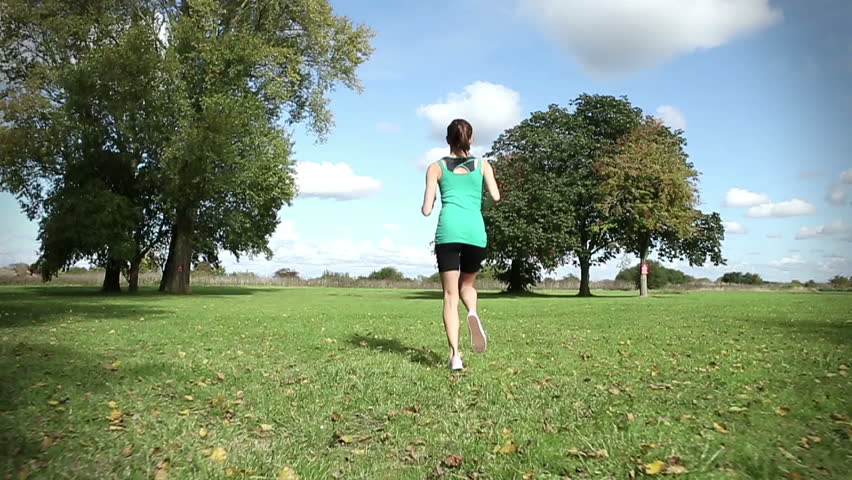 Young female runner in slow motion moving along a running field