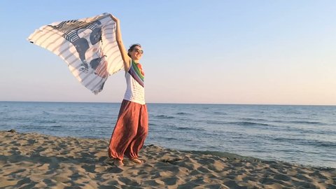 Young woman dancing on the beach with a scarf in the blowing wind. Super slow motion shot, Long shot, Establishing Shot in Montenegro, Adriatic sea coast, Ade Bojano. Contains adult (30s-40s).