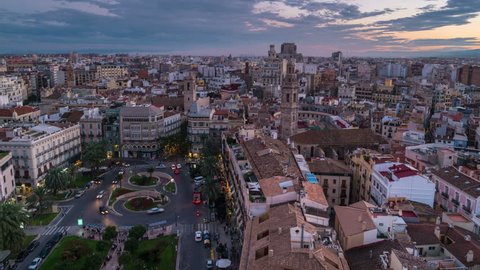 Aerial view of Valencia, Spain at sunset. Illuminated Plaza de la Reina with many cafes and restaurants and very popular among tourists. Cloudy colorful sky. Time-lapse