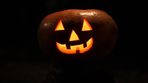 Funny Halloween pumpkin face with glowing candle in Grass. Close Up.