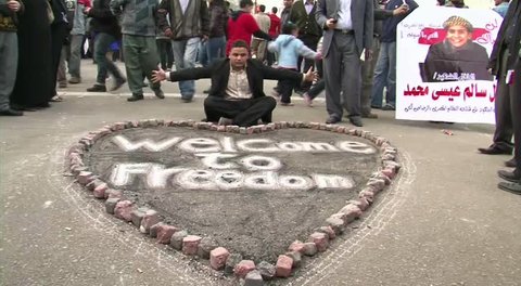 CAIRO - CIRCA FEB 2011: Man with "Welcome to Freedom" sign at Tahrir Square, circa February 2011, Cairo, Egypt. Tahrir Square was the focal point of the 2011 Egyptian Revolution where demonstrations grew to 250,000 plus people by day 6, January 31, 2011.