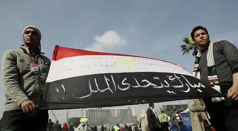 CAIRO - CIRCA JAN 2011: Two men carrying Egyptian flag, Tahrir Square, circa January 2011, Cairo, Egypt. Tahrir Square was the focal point of the 2011 Egyptian Revolution where demonstrations grew to 250,000 plus people by day 6, January 31, 2011.