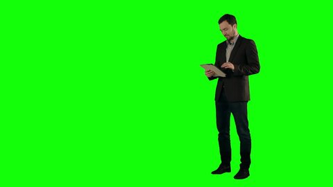 Happy Young Man Using Digital Tablet  on a Green Screen, Chroma Key. Professional shot on BMCC RAW with high dynamic range. You can use it e.g in your commercial video, business video, office theme.
