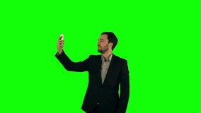 Businessman taking a selfie on a Green Screen, Chroma Key. Professional shot on BMCC RAW with high dynamic range. You can use it e.g in your commercial video, business video, office theme.
