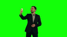 Young man taking a selfie photo with his smartphone on a Green Screen, Chroma Key. Professional shot on BMCC RAW with high dynamic range. You can use it e.g in your commercial video, business video
