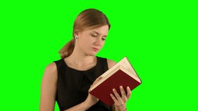 Young beautiful girl reading a book on laptop on a Green Screen, Chroma Key.  Professional shot on BMCC RAW with high dynamic range. You can use it e.g in your commercial video, business video, office