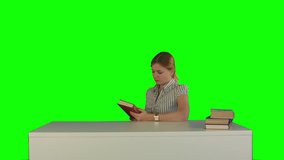 Female student reading a book for finding information on a Green Screen, Chroma Key. Professional shot on BMCC RAW with high dynamic range. You can use it e.g in your commercial video, business video