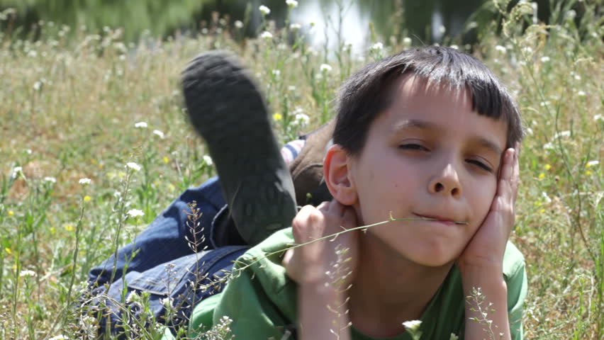 The boy lies in the grass. Summer.