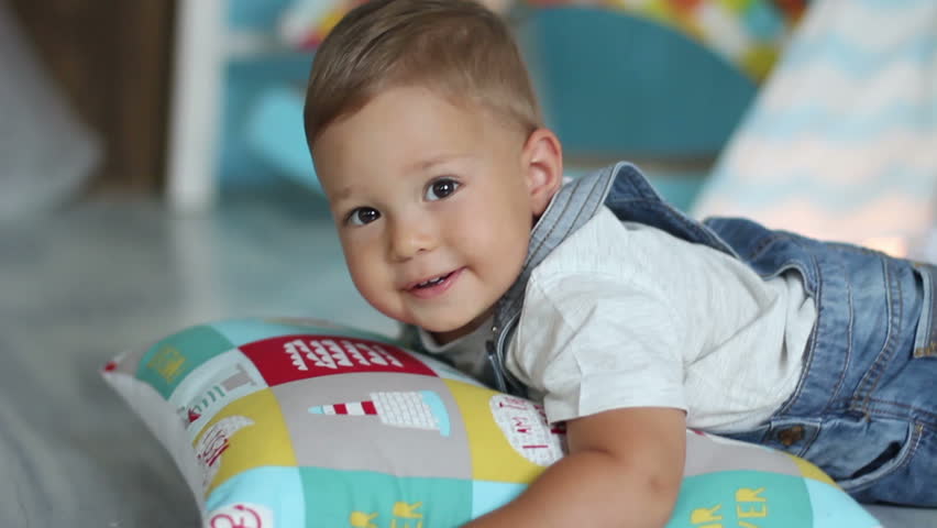 baby on pillow smiling to camera when his father  tickling his heels 