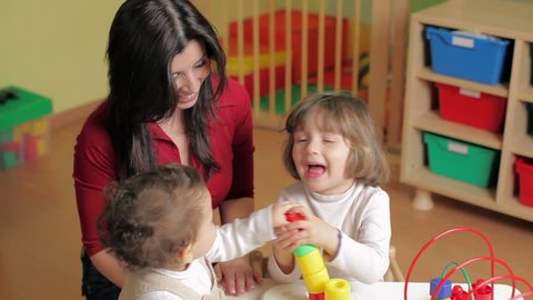 Kindergarten with teacher, toddler and 2-3 year girl playing with blocks toy
