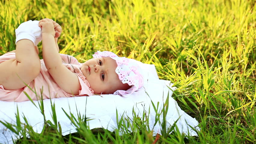 Baby lying on the grass and look at camera 