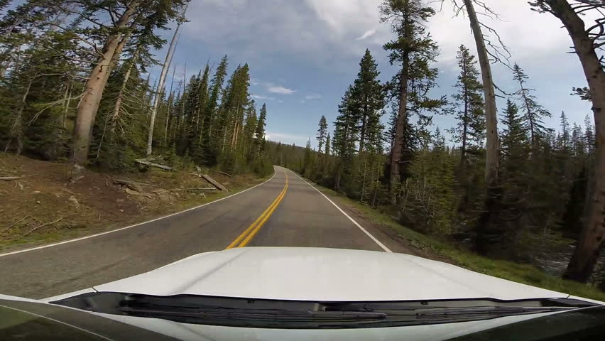 YELLOWSTONE, WYOMING - Driving point of view from front window of moving car. Vacation travel. 3 million visitors each year.